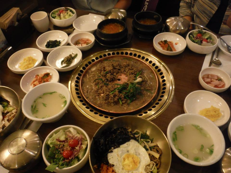 A table laden with various banchan and Korean dishes at Sariwon restaurant, showcasing the abundance and variety of a traditional Korean meal.