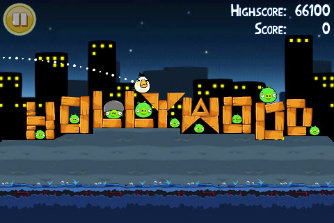 alt text: Screenshot of the Angry Birds game, showing the birds launching themselves at a structure built by the pigs.