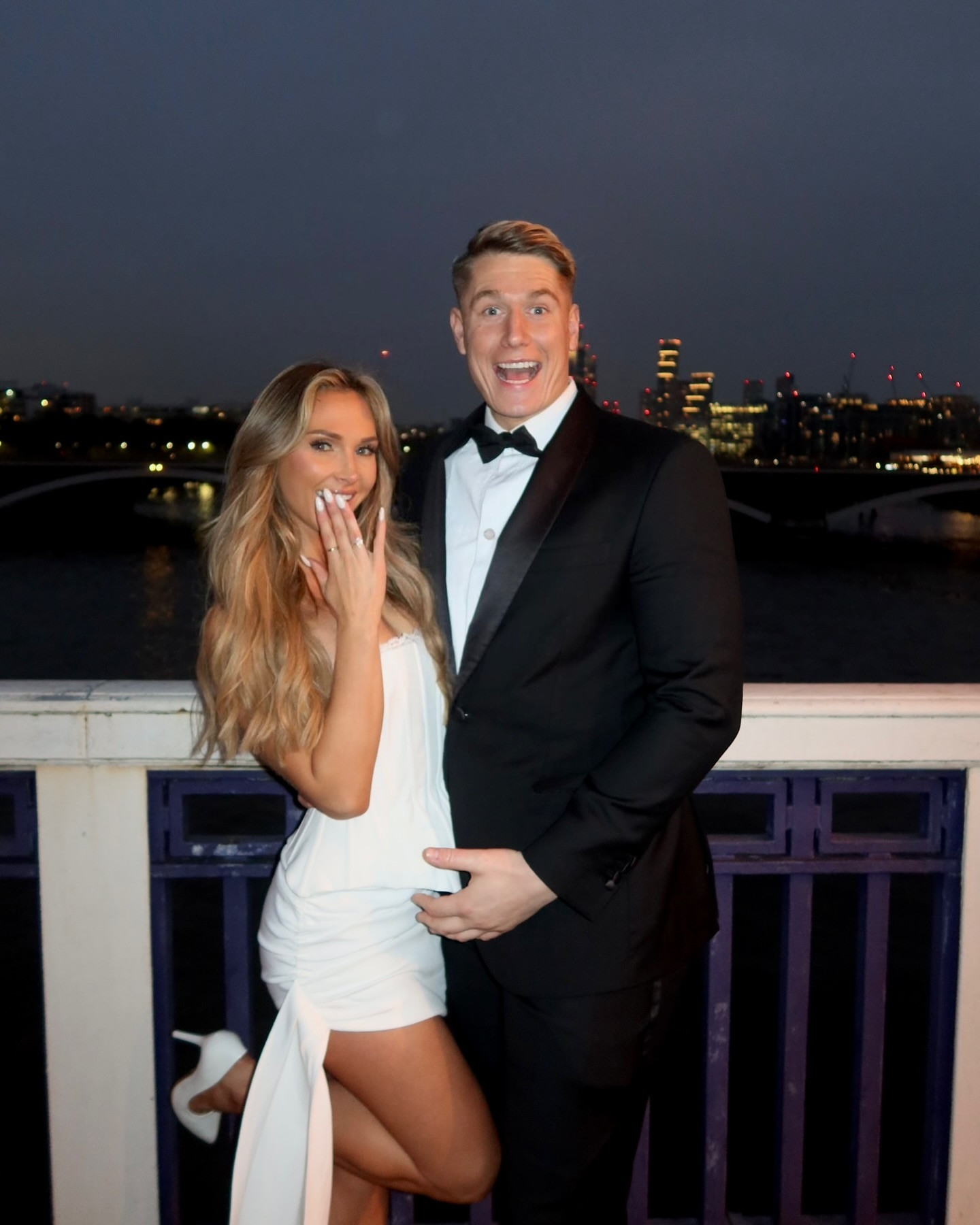 a man in a tuxedo and a woman in a white dress pose for a picture