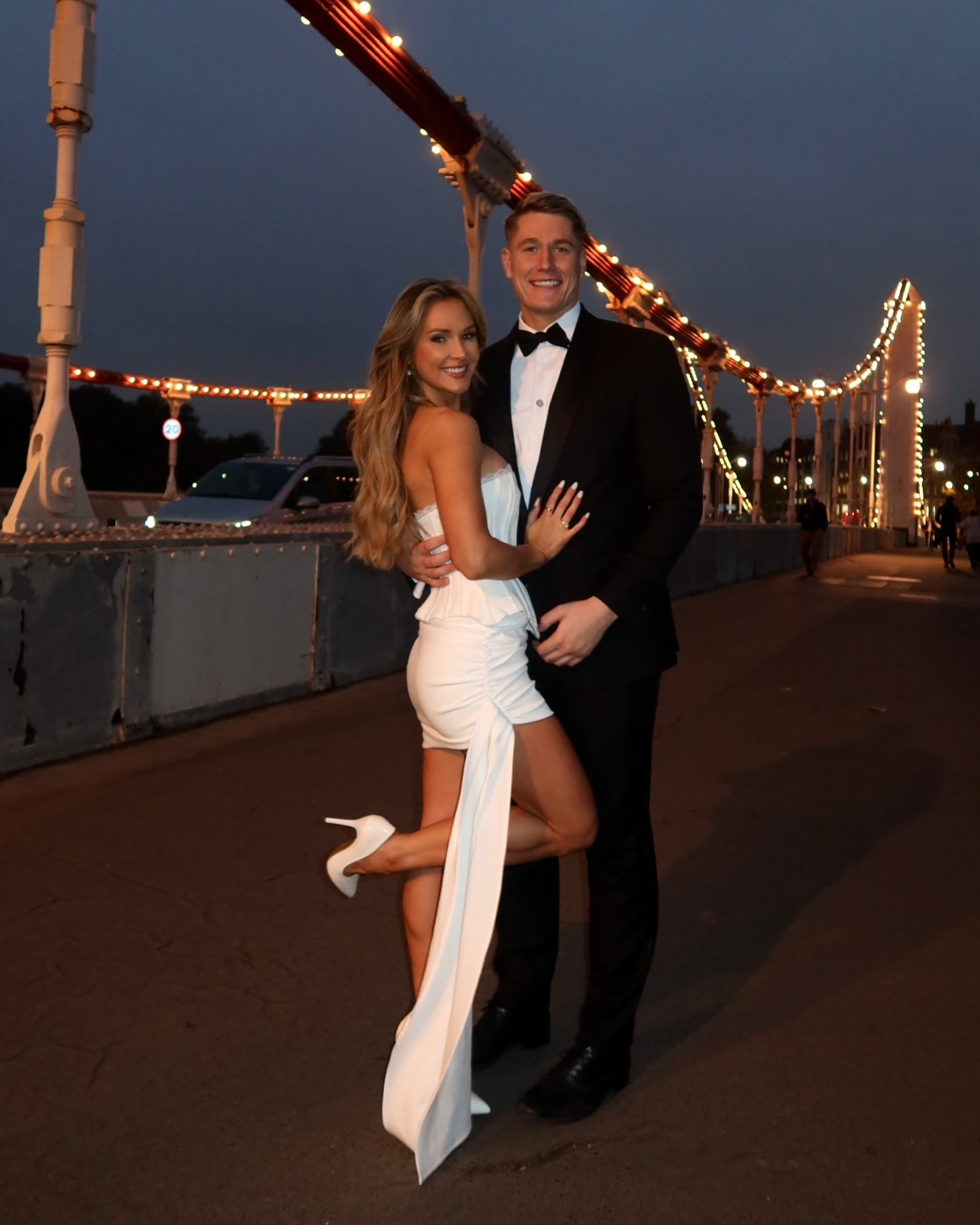 a man in a tuxedo and a woman in a white dress pose for a picture