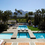 Aerial view of multiple swimming pools surrounded by palm trees and sun loungers.