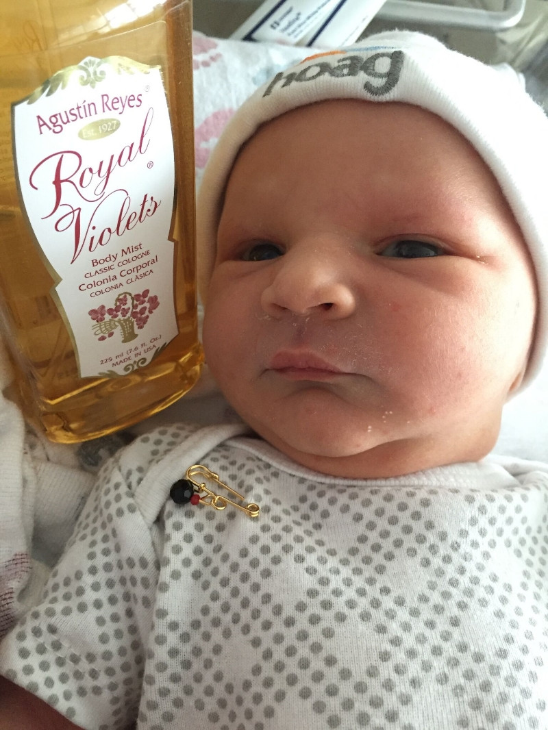 A baby with traditional Cuban gifts of violetas and an azabache.