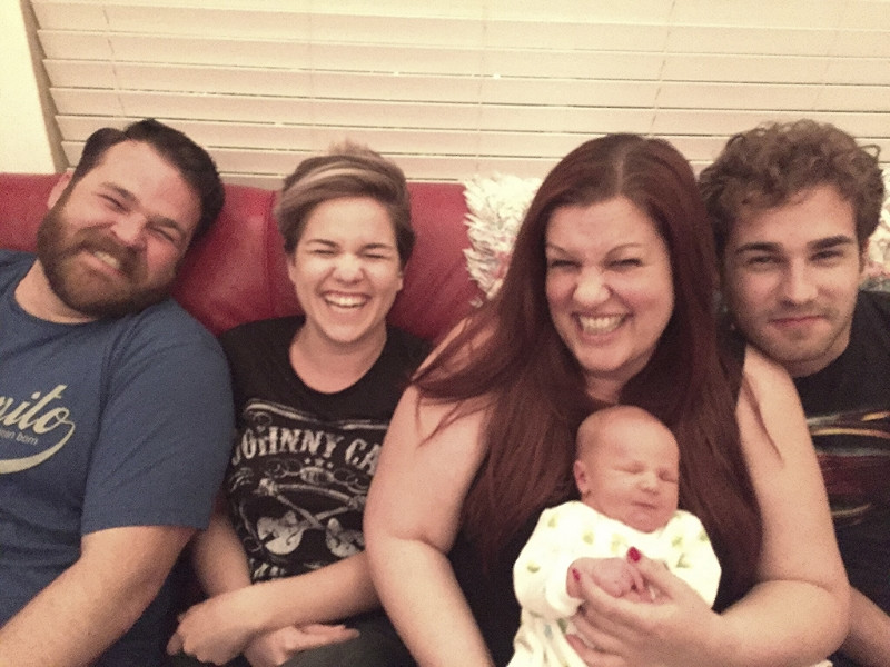 A family gathered around a table, celebrating with a newborn.