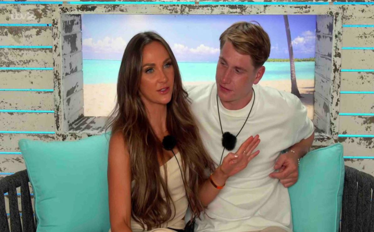 a man and a woman are sitting on a couch with a picture of a beach in the background