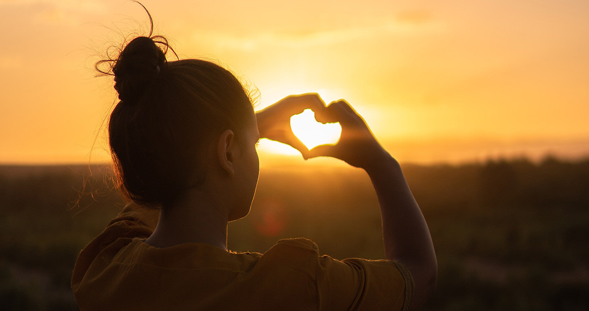 Woman makes heart shape with hands.