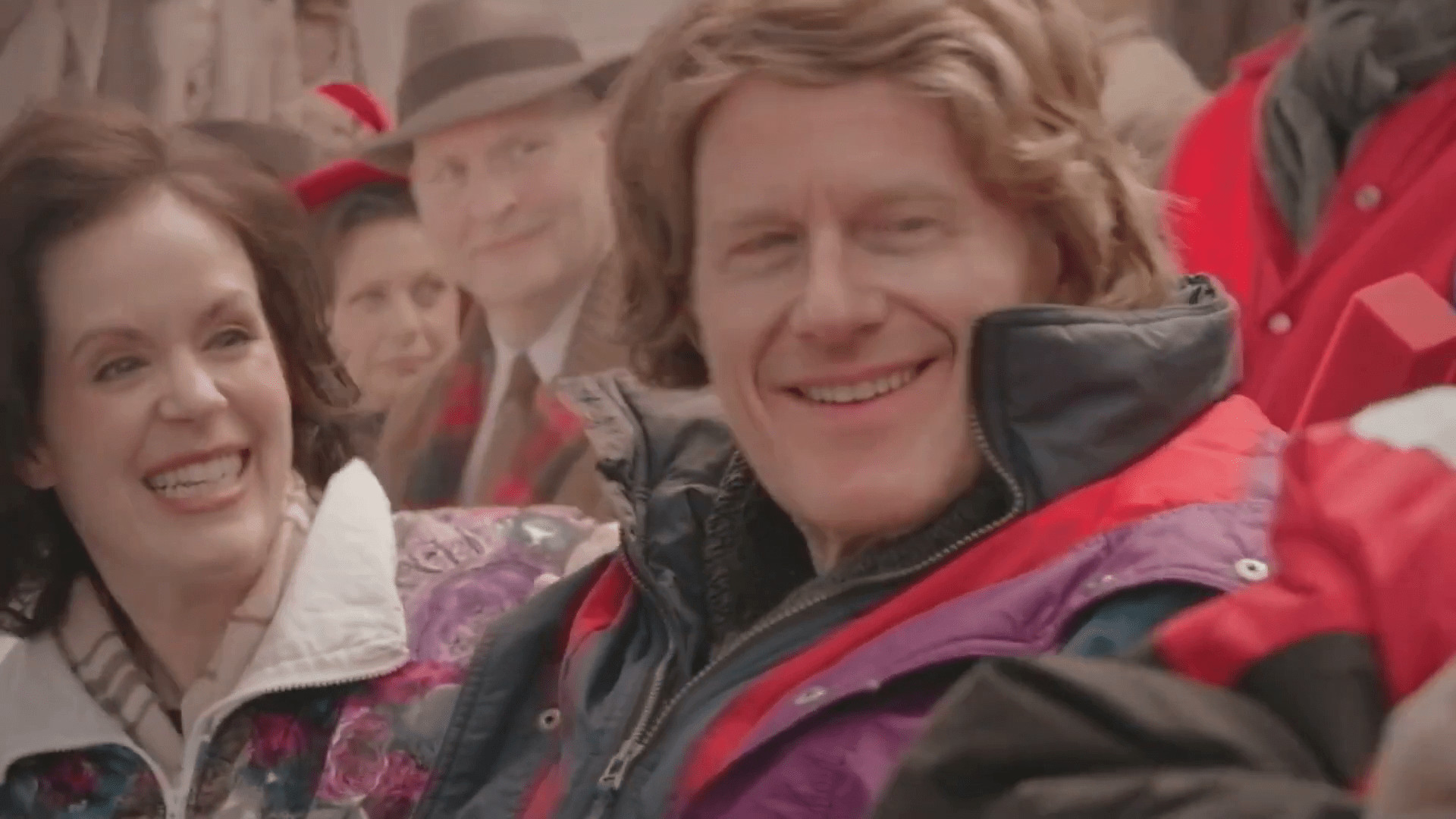 Ed Begley Jr. and actress in vintage coats and windbreaker, showcasing a family's multi-generational Chiefs fandom in a still from A Chiefs Love Story Hallmark movie.