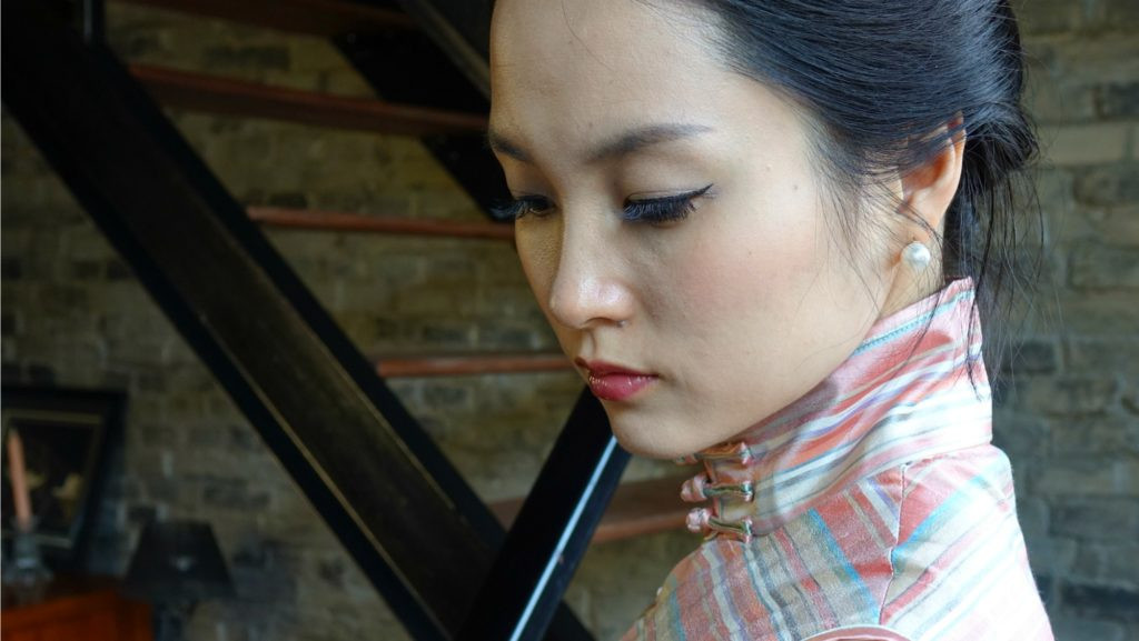 A woman wearing a pink striped qipao, inspired by the film In the Mood for Love.