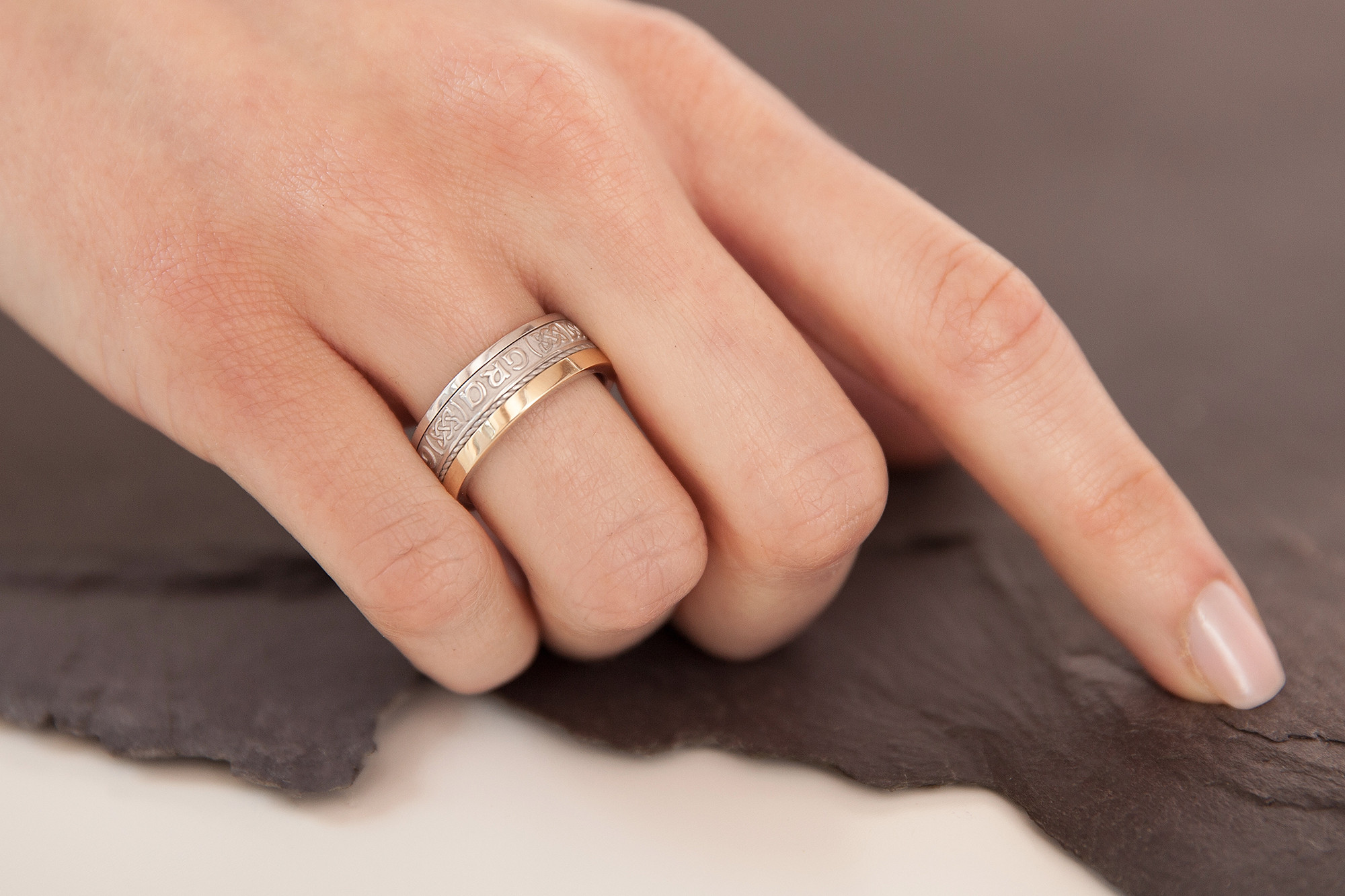 alt text: Two hands intertwined, showcasing matching rings with a Celtic knot design.