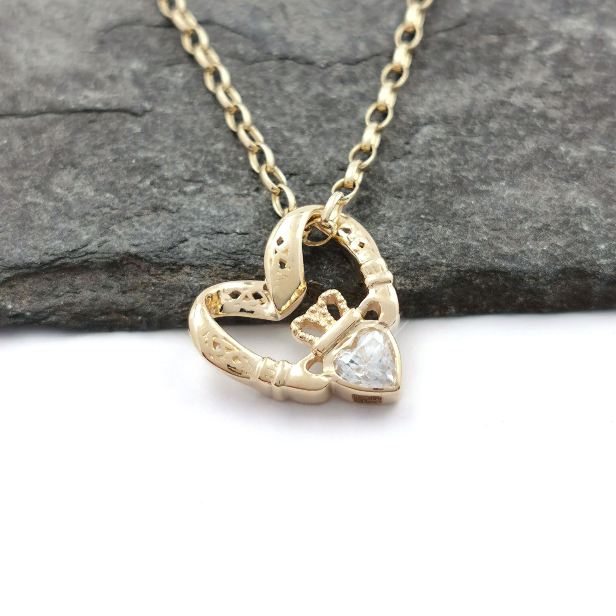 alt text: A 9k gold Claddagh pendant with a floating heart in the center, adorned with cubic zirconia.